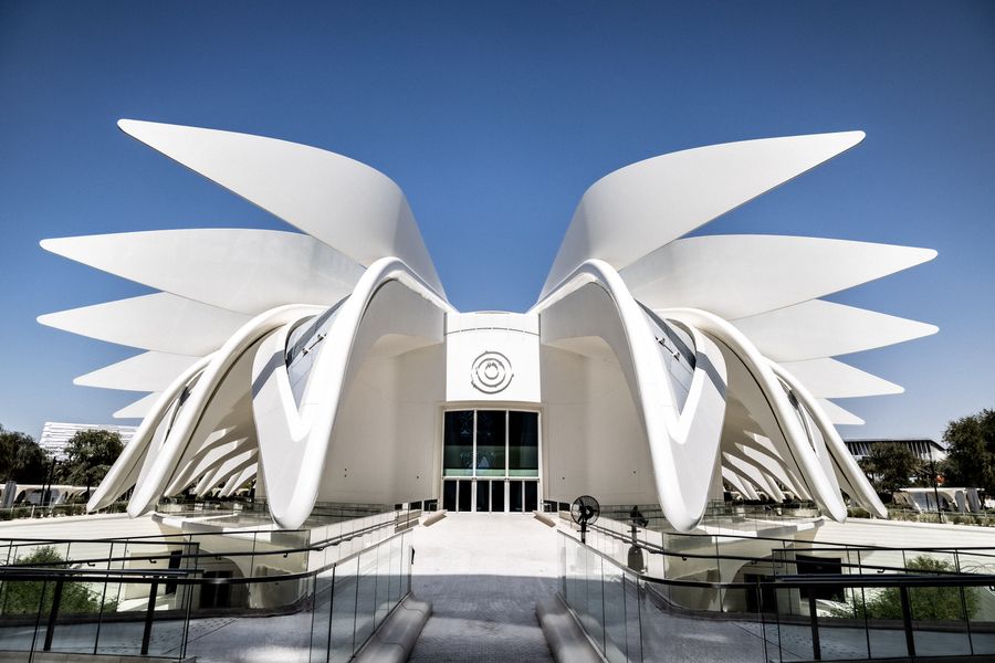Sculptural white building with sweeping wing-shaped roof forms
